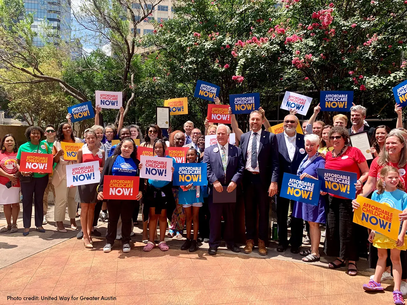 Group of legislators and supporters holding signs for the Affordable Childcare Now campaign in Austin, TX.