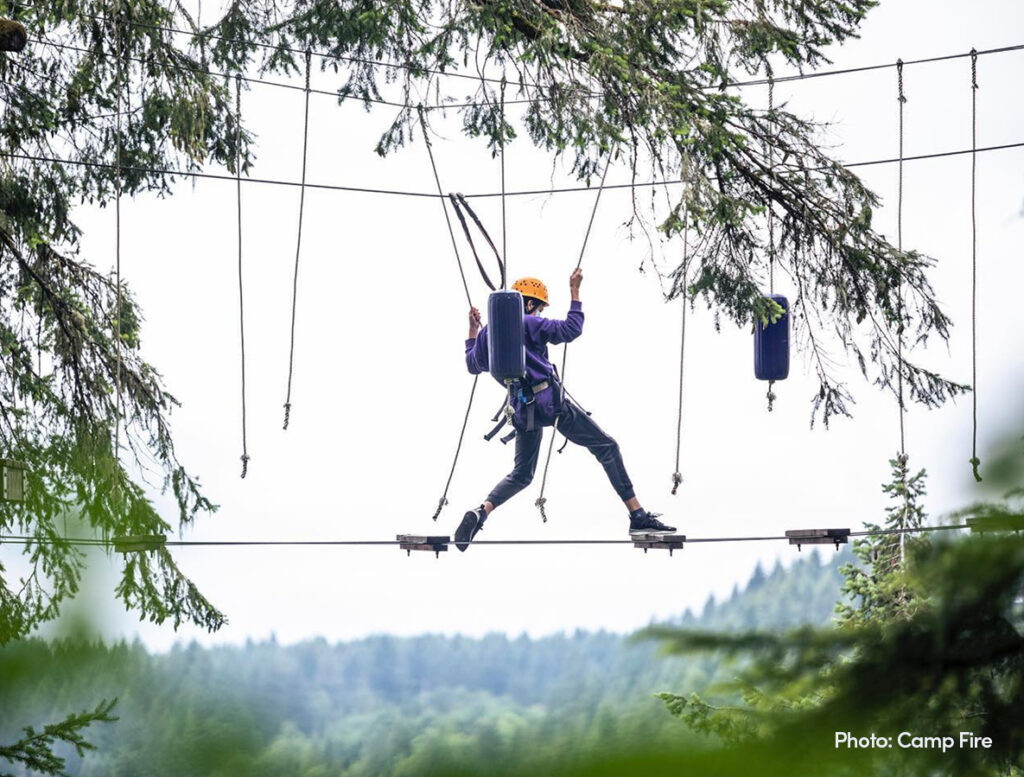Young person doing an outdoor rope walking activity.