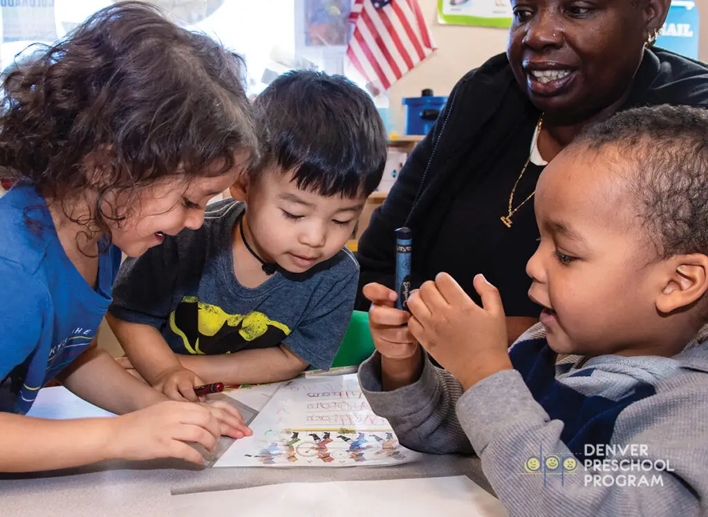 A woman helping small children with an art project at Denver Preschool Program.