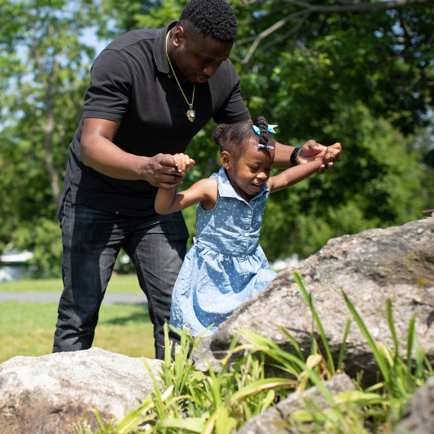 Adult helping child climb a rock