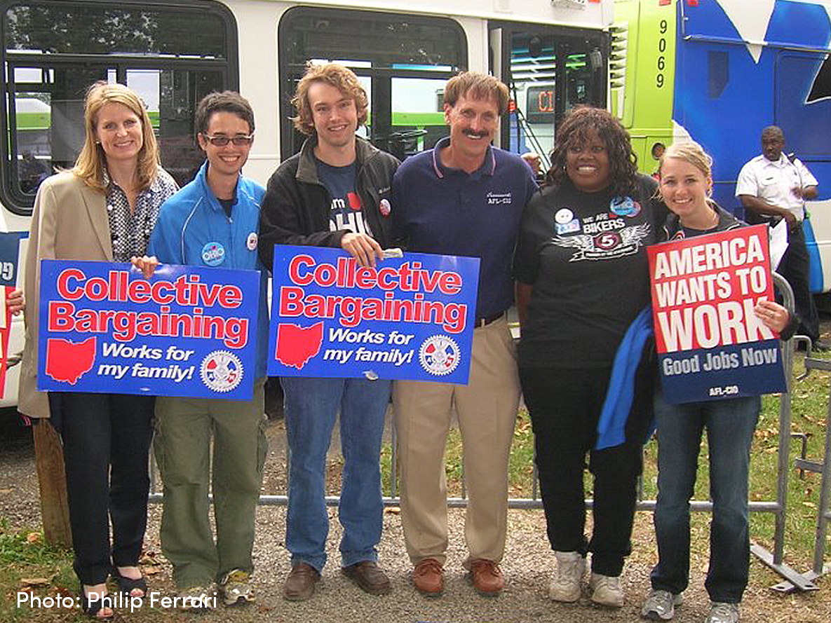 Phil standing with others holding signs supporting collective bargaining.