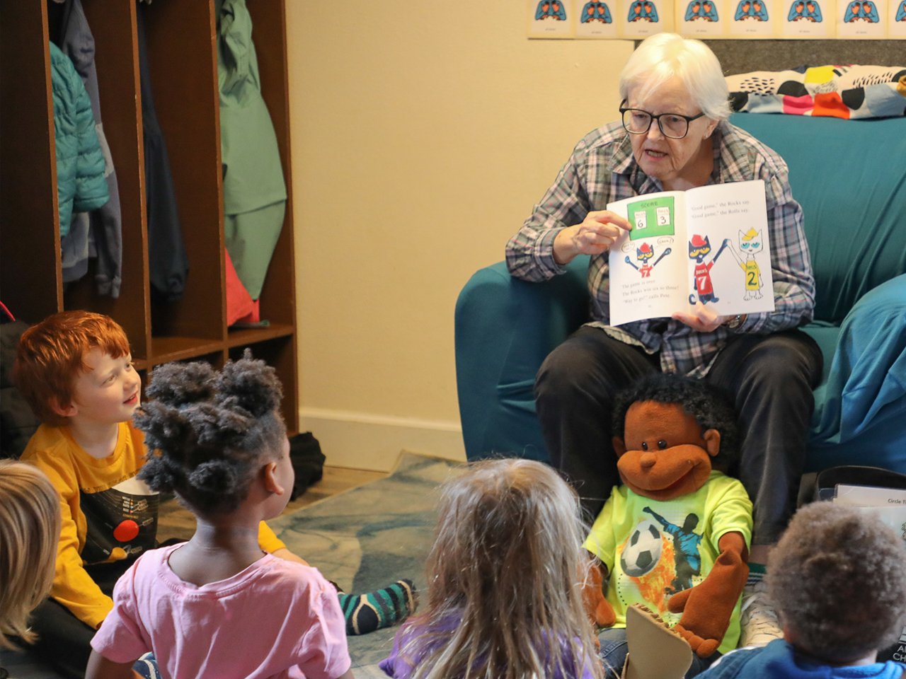 Older adult reading picture book to group of young children