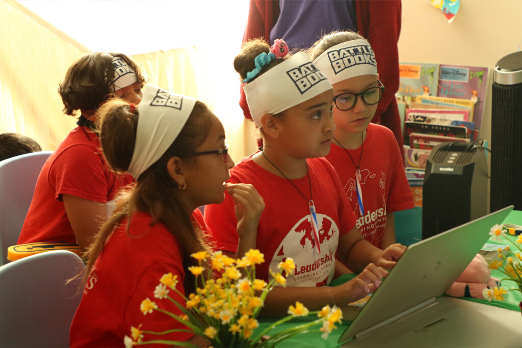 Kids in matching team gear in front of a computer together