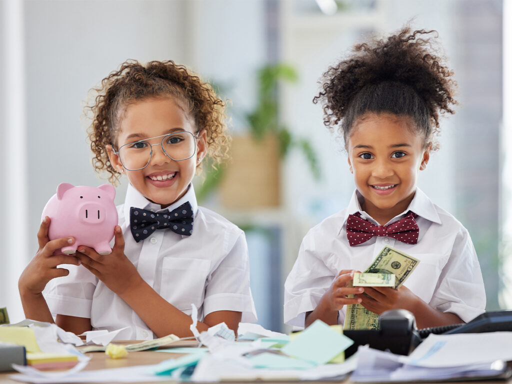 Smiling kids in bow ties holding money and a piggy bank