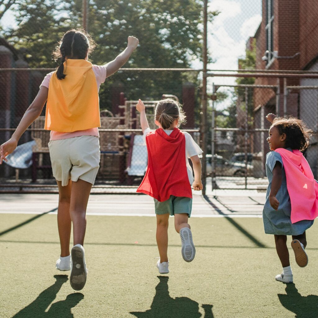 three different aged girls running in capes