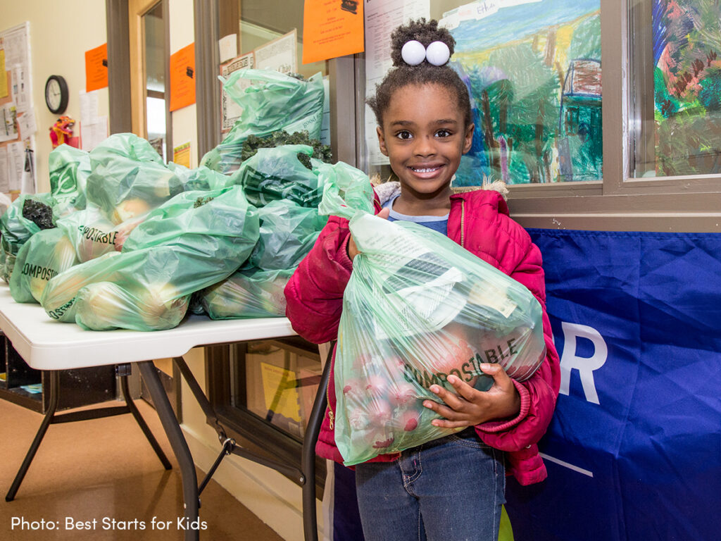 Happy child holding back of produce.