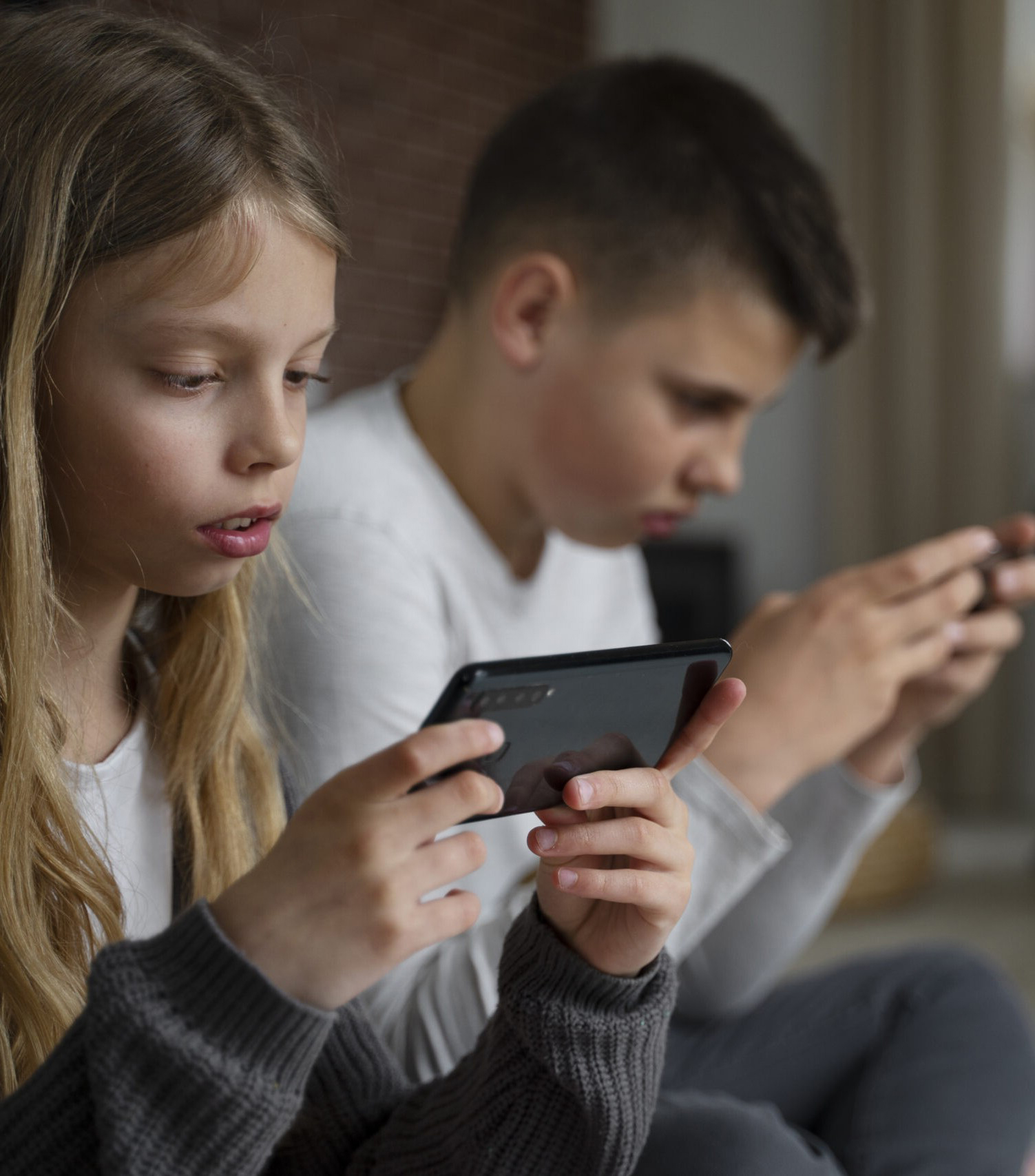 Two sitting next to each other focused on phones.